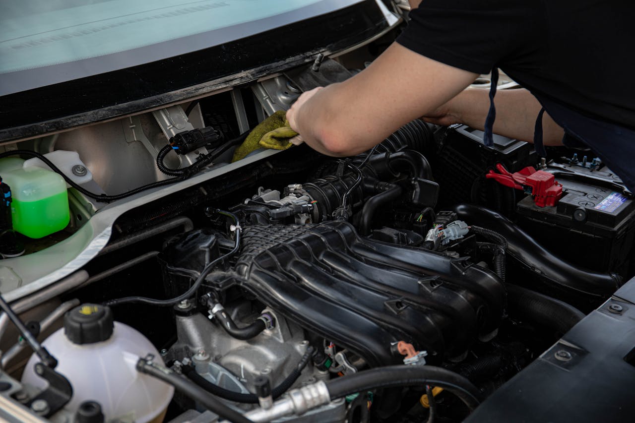 Close-up of a mechanic working on a car engine in a workshop setting.
